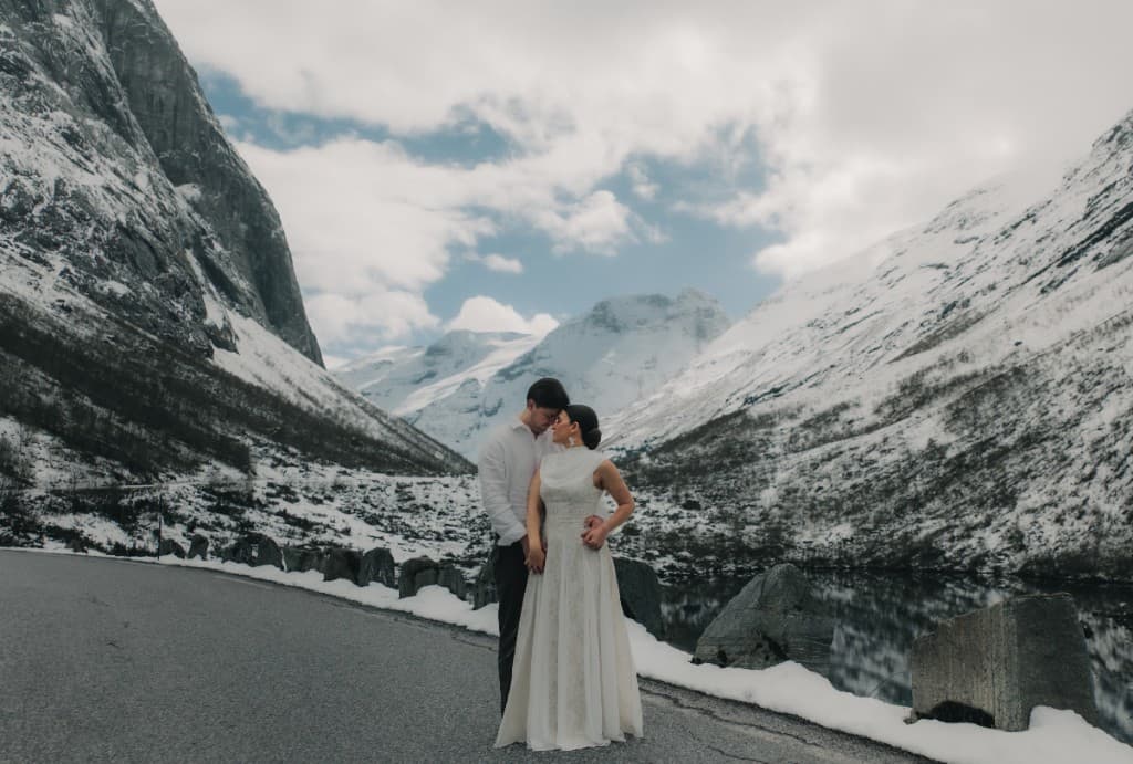 Styled wedding shoot — couple on a mountain road with fjord and peaks in Stranda